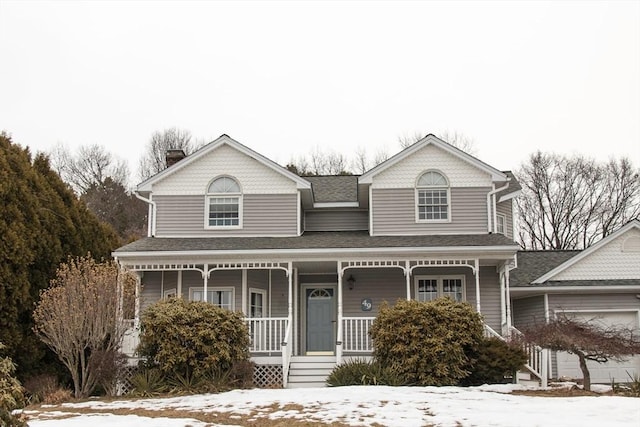 view of front facade with a garage, covered porch, and roof with shingles