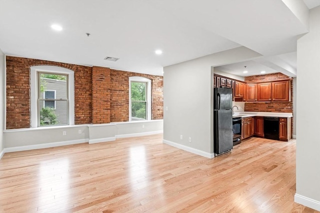 72 River St Unit 5, Haverhill, MA 01832 - unfurnished living room featuring plenty of natural light, light wood-style floors, brick wall, a sink, and baseboards