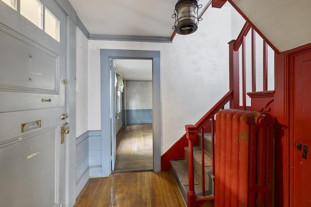 50 Humphrey St, Marblehead, MA 01945 - foyer featuring hardwood / wood-style floors, radiator heating unit, stairway, a wainscoted wall, and a decorative wall