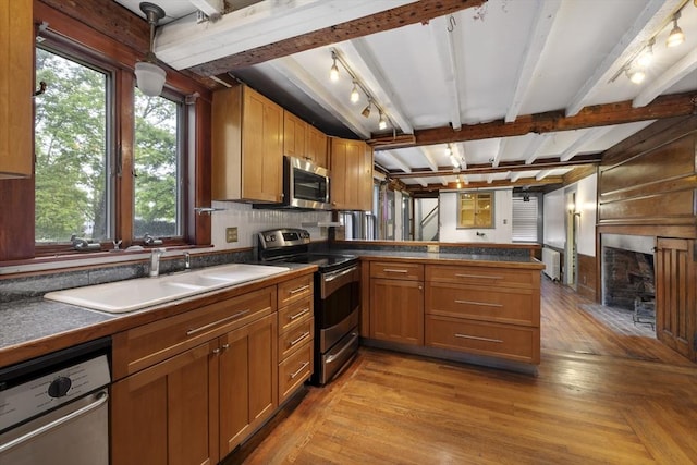 50 Humphrey St, Marblehead, MA 01945 - kitchen featuring stainless steel appliances, dark countertops, a peninsula, a sink, and a fireplace