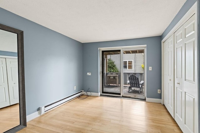 733 W Main Unit G, Barnstable, MA 02630 - unfurnished bedroom with a baseboard radiator, access to exterior, baseboards, light wood finished floors, and a textured ceiling