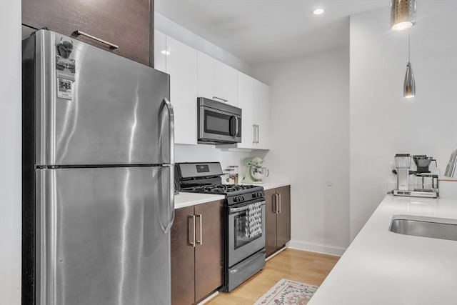 1 Brook Rd Unit 215, Quincy, MA 02169 - kitchen featuring stainless steel appliances, a sink, light wood finished floors, light countertops, and white cabinetry