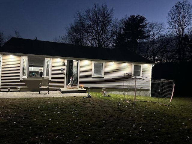 back of house at twilight featuring a yard and a patio area