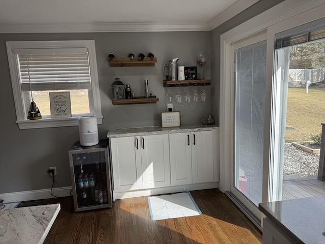 bar featuring wine cooler, wood finished floors, baseboards, a dry bar, and crown molding