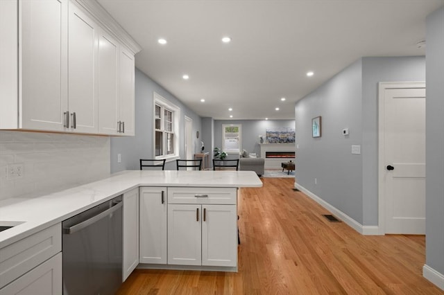 kitchen with stainless steel dishwasher, white cabinets, light wood-style floors, recessed lighting, and open floor plan