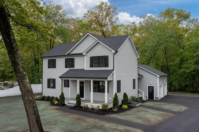 view of front of house with asphalt driveway, covered porch, roof with shingles, a garage, and fence