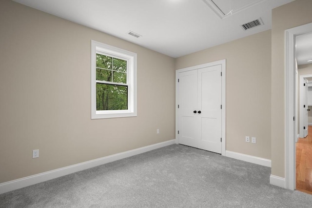 unfurnished bedroom featuring attic access, carpet floors, baseboards, and a closet