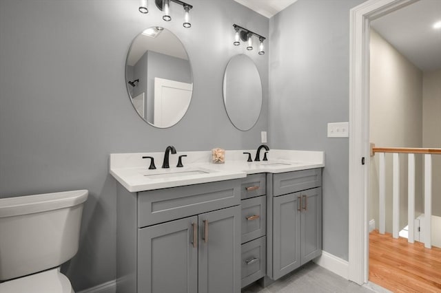 full bathroom with toilet, double vanity, and baseboards