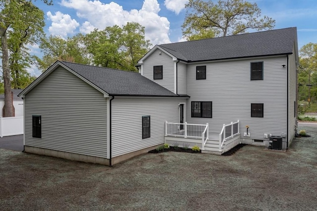 back of house featuring a shingled roof, a deck, and central AC unit