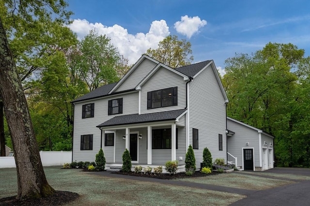 view of front of house featuring asphalt driveway, covered porch, fence, and roof with shingles