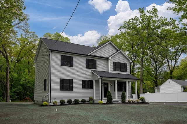 traditional-style home with covered porch and a shingled roof
