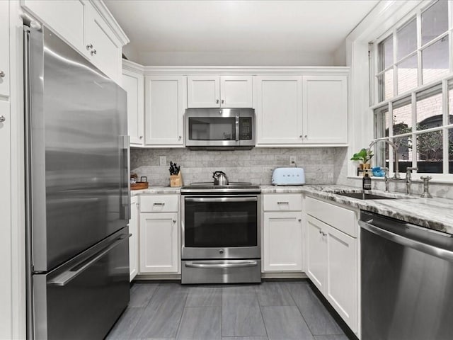 kitchen with tasteful backsplash, appliances with stainless steel finishes, white cabinets, and a sink