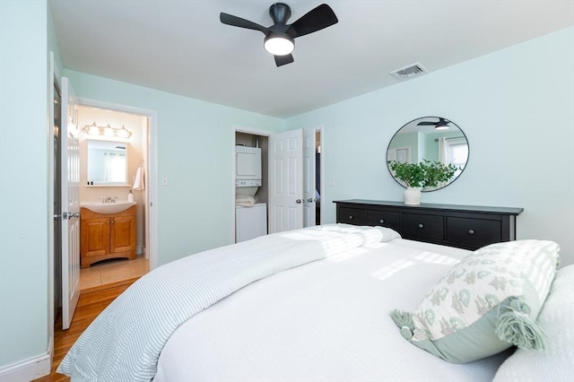 bedroom with ceiling fan, sink, light wood-type flooring, and ensuite bath