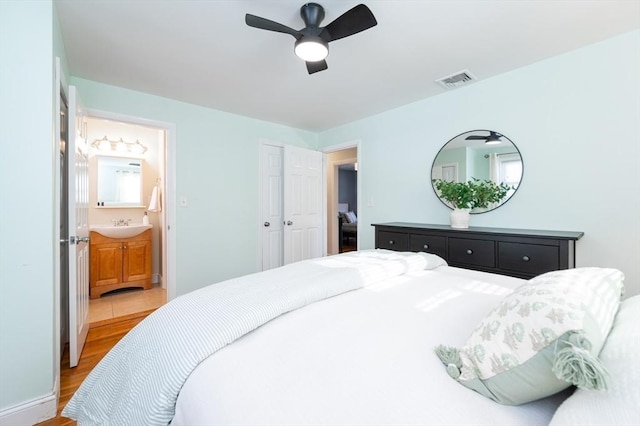 bedroom featuring sink, ensuite bath, ceiling fan, and light wood-type flooring