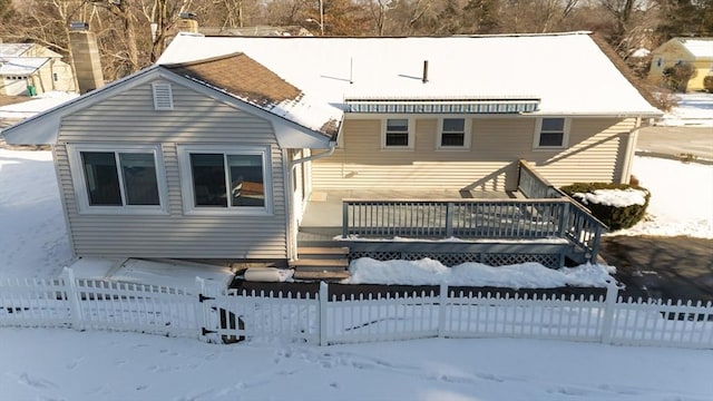 snow covered rear of property with a wooden deck