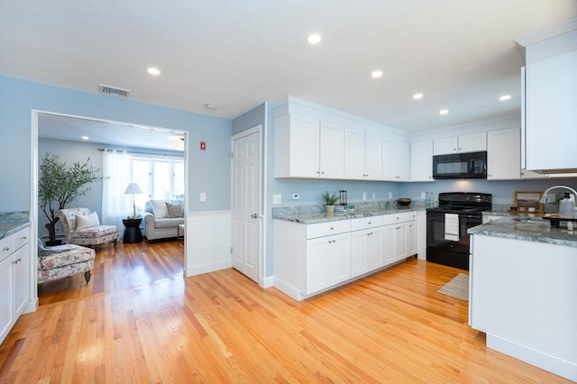 kitchen featuring light wood-type flooring, white cabinets, sink, and black appliances