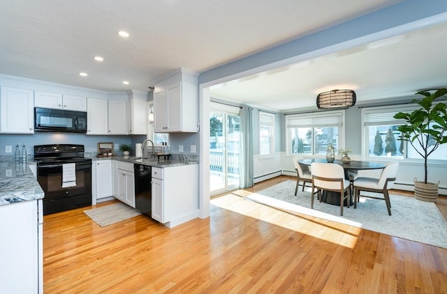 kitchen featuring sink, white cabinetry, light stone counters, black appliances, and light wood-type flooring