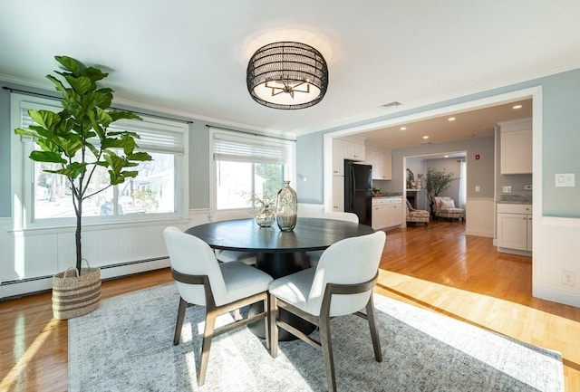 dining room with crown molding, a baseboard radiator, and light wood-type flooring