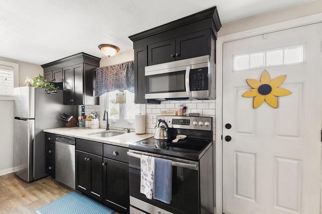 53 Avon St, Taunton, MA 02780 - kitchen with stainless steel appliances, a sink, decorative backsplash, light wood-style floors, and dark cabinets