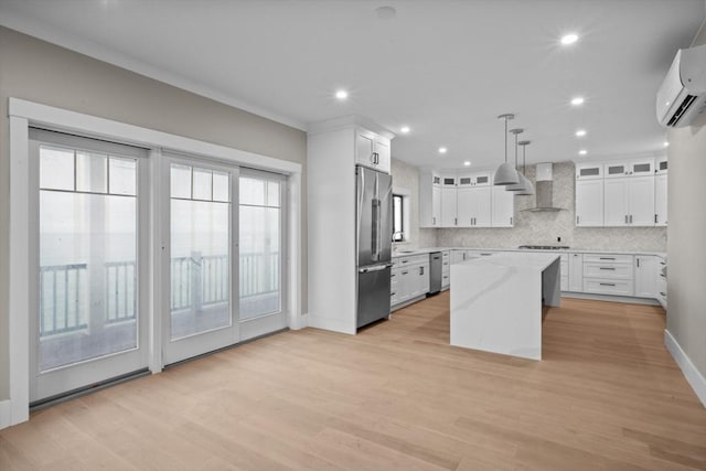 kitchen with wall chimney range hood, light hardwood / wood-style flooring, white cabinets, a center island, and hanging light fixtures