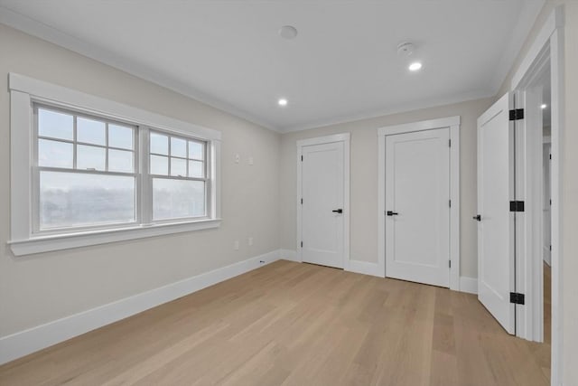 unfurnished bedroom with multiple closets, crown molding, and light wood-type flooring