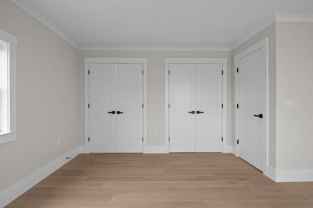 interior space featuring ornamental molding, light hardwood / wood-style flooring, and multiple closets