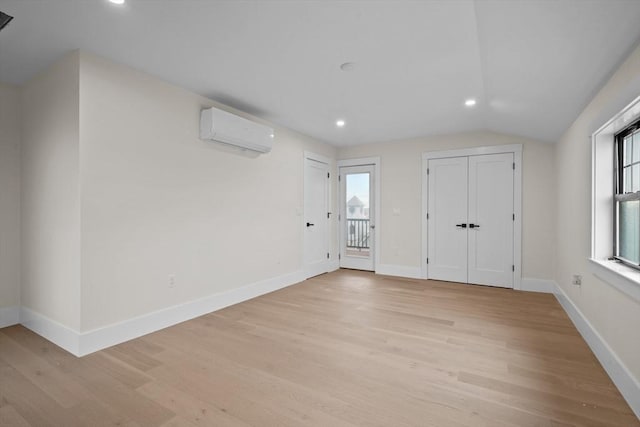 interior space with light hardwood / wood-style floors, lofted ceiling, and a wall mounted AC