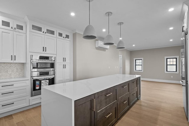 kitchen featuring pendant lighting, a center island, white cabinetry, stainless steel appliances, and a wall unit AC