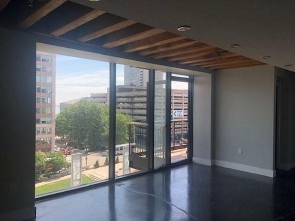 unfurnished room with finished concrete flooring, baseboards, and a view of city