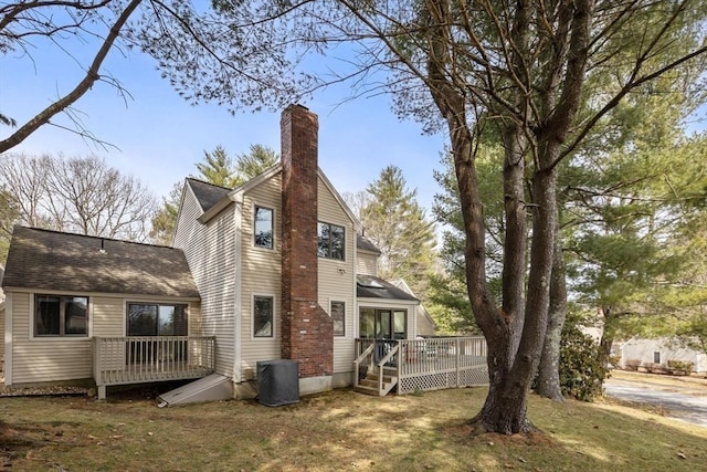 rear view of house featuring a lawn, a deck, and a chimney