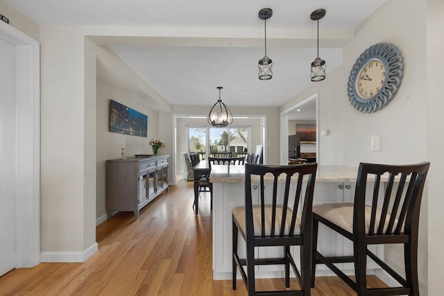 dining space featuring a notable chandelier, light wood-type flooring, and baseboards