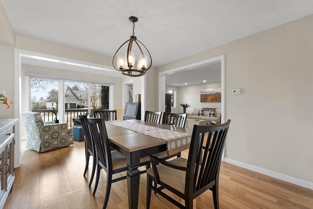 dining space featuring an inviting chandelier, baseboards, and light wood-style floors