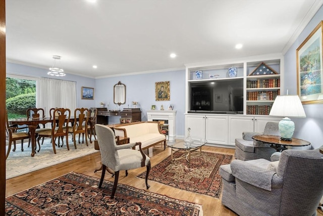 living room featuring ornamental molding, light wood-style floors, a fireplace, a chandelier, and recessed lighting