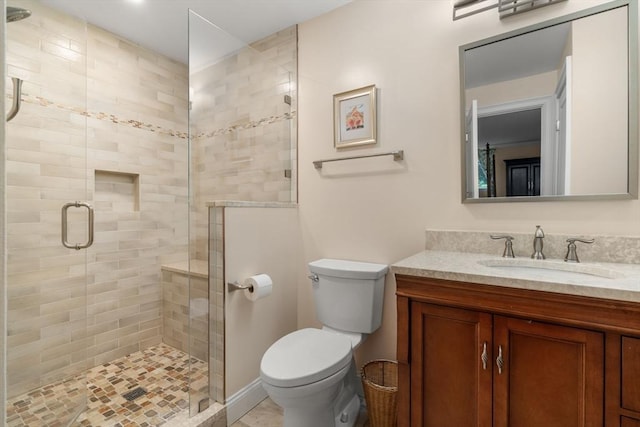bathroom featuring toilet, a stall shower, and vanity