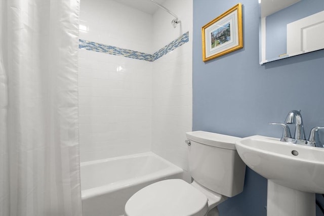 bathroom with toilet, shower / tub combo with curtain, and a sink
