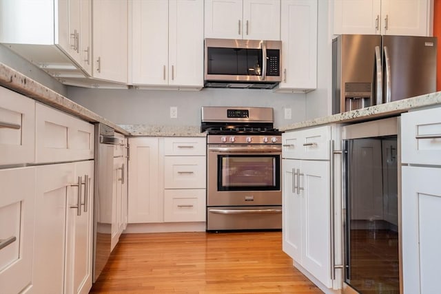 41 Washington Unit C, Newburyport, MA 01950 - kitchen with appliances with stainless steel finishes, light wood-type flooring, light stone countertops, and white cabinets