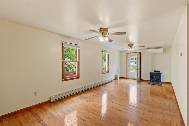 128 Arthur Ave, Athol, MA 01331 - empty room with baseboard heating, a wood stove, a wall unit AC, and healthy amount of natural light