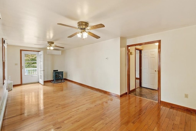 128 Arthur Ave, Athol, MA 01331 - unfurnished living room featuring a wood stove, a wall mounted AC, a ceiling fan, light wood-style floors, and baseboards
