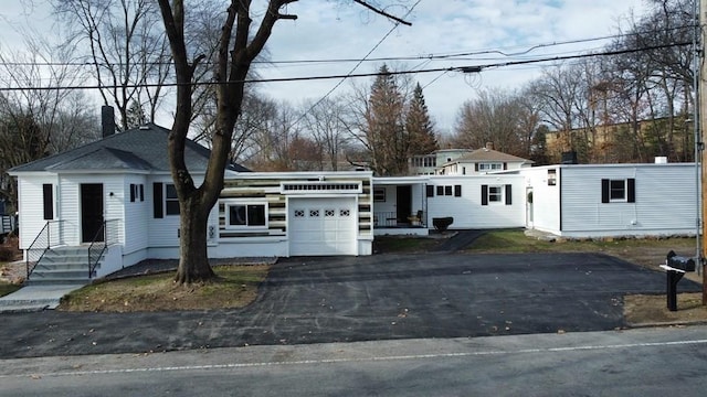 view of front of property featuring an attached garage, driveway, and a chimney