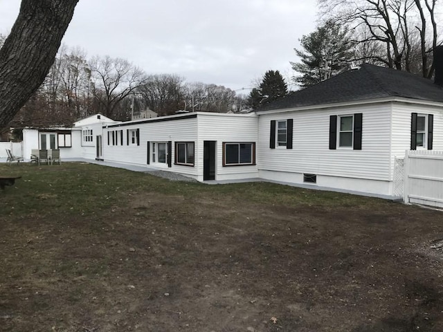back of house featuring a lawn and fence
