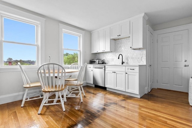 11 Barr St, Salem, MA 01970 - kitchen featuring dishwasher, light wood finished floors, tasteful backsplash, white cabinets, and light countertops