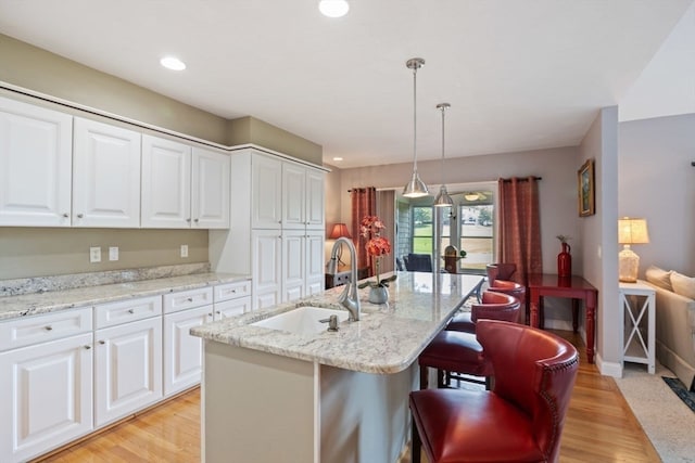 kitchen with sink, light hardwood / wood-style flooring, white cabinets, and pendant lighting