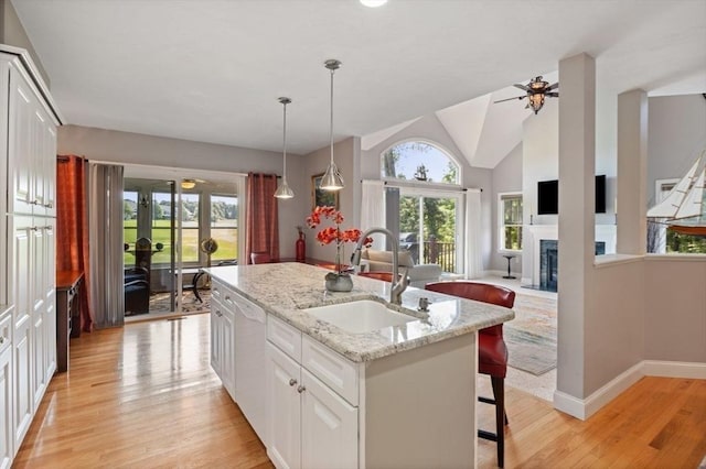 kitchen featuring an island with sink, sink, white cabinets, white dishwasher, and light hardwood / wood-style flooring