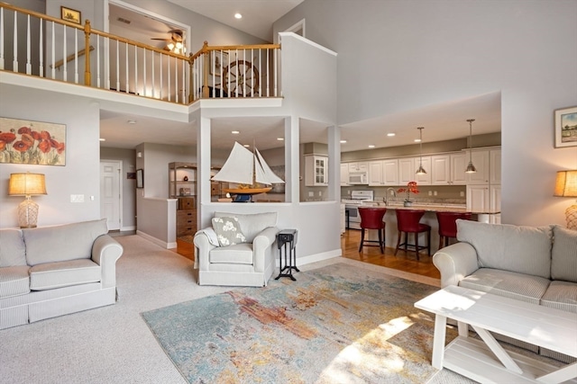 living room with sink, ceiling fan, hardwood / wood-style floors, and a towering ceiling