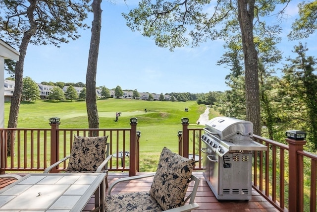 wooden deck featuring a lawn and a grill