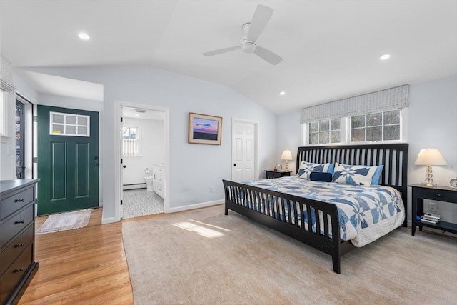 bedroom featuring lofted ceiling, a baseboard heating unit, light wood-style flooring, ensuite bathroom, and baseboards