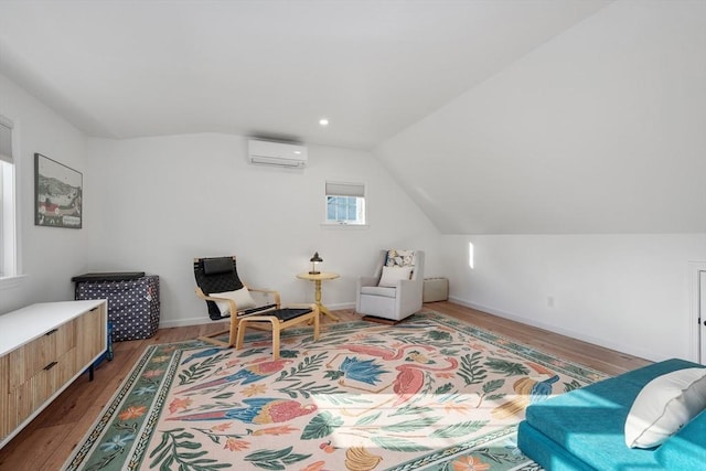 sitting room featuring a wall mounted AC, lofted ceiling, wood finished floors, and baseboards