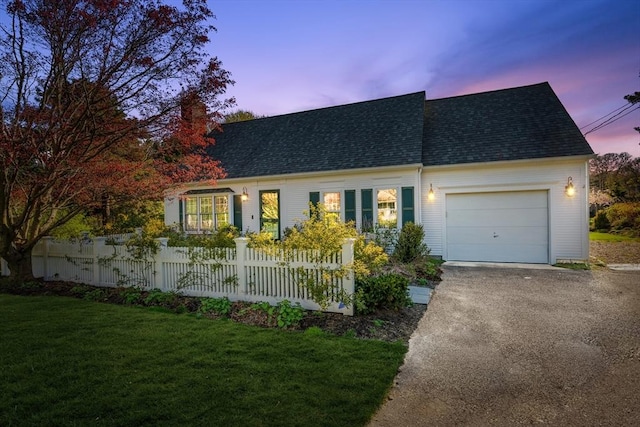 cape cod house featuring roof with shingles, asphalt driveway, and an attached garage