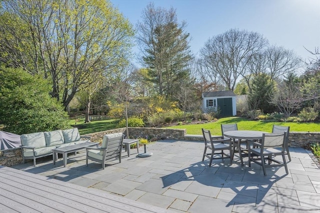 view of patio / terrace featuring outdoor dining area, a shed, an outdoor living space, and an outbuilding