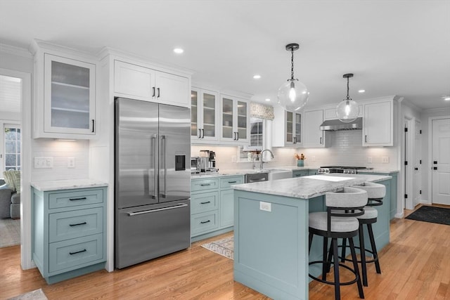 kitchen featuring stainless steel built in fridge, under cabinet range hood, white cabinets, tasteful backsplash, and recessed lighting